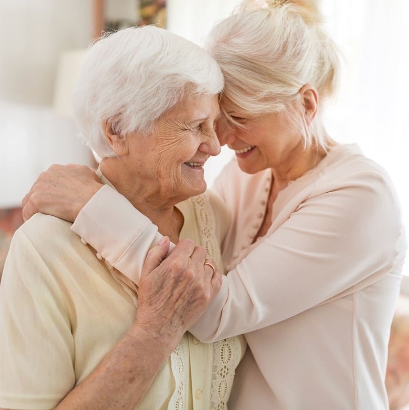 an elderly lady hugging her daughter an elderly lady hugging her daughter