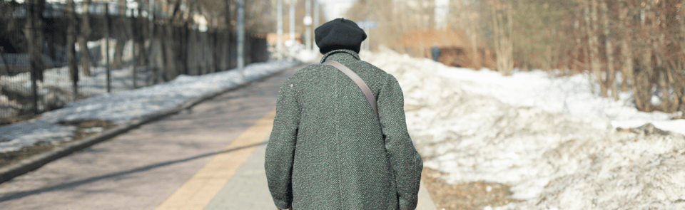 Elderly person walking alone down the street.