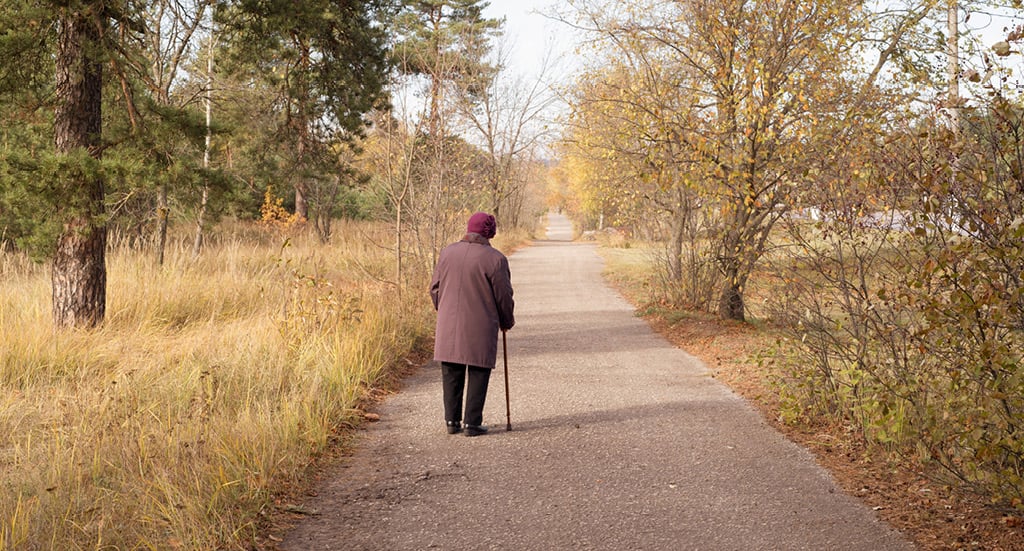 Woman with cane walking down winter path Woman with cane walking down winter path