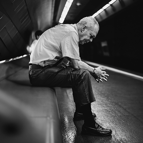 Homme âgé assis sur un banc dans un tunnel de métro
