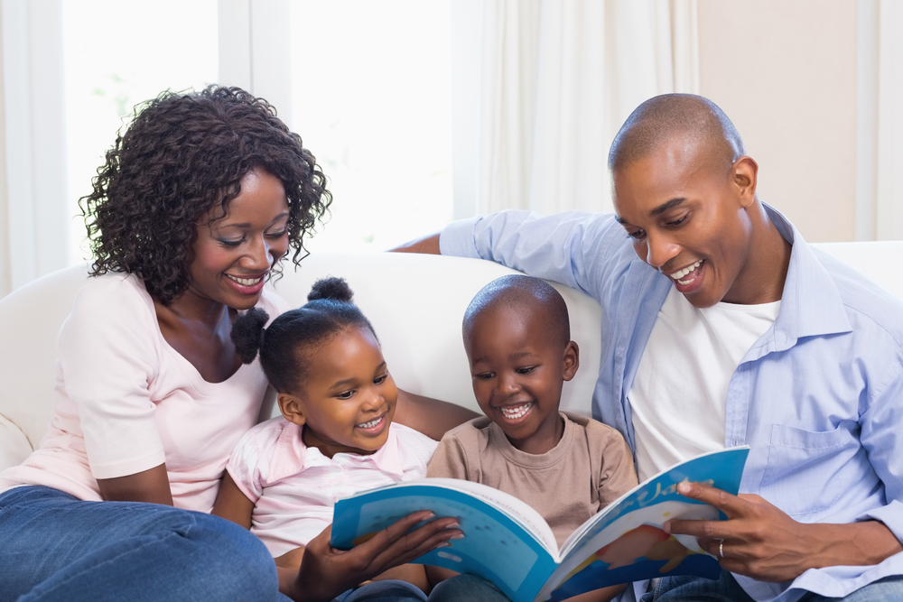 Happy family on the couch reading storybook at home in the living room Happy family on the couch reading storybook at home in the living room