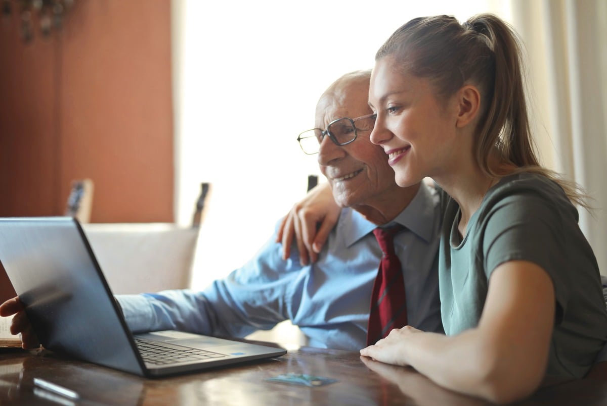 an elderly man with a woman looking at computer