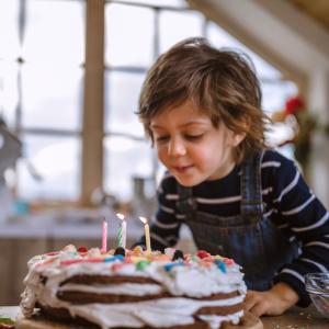 Young boy blowing his birthday cake candles.